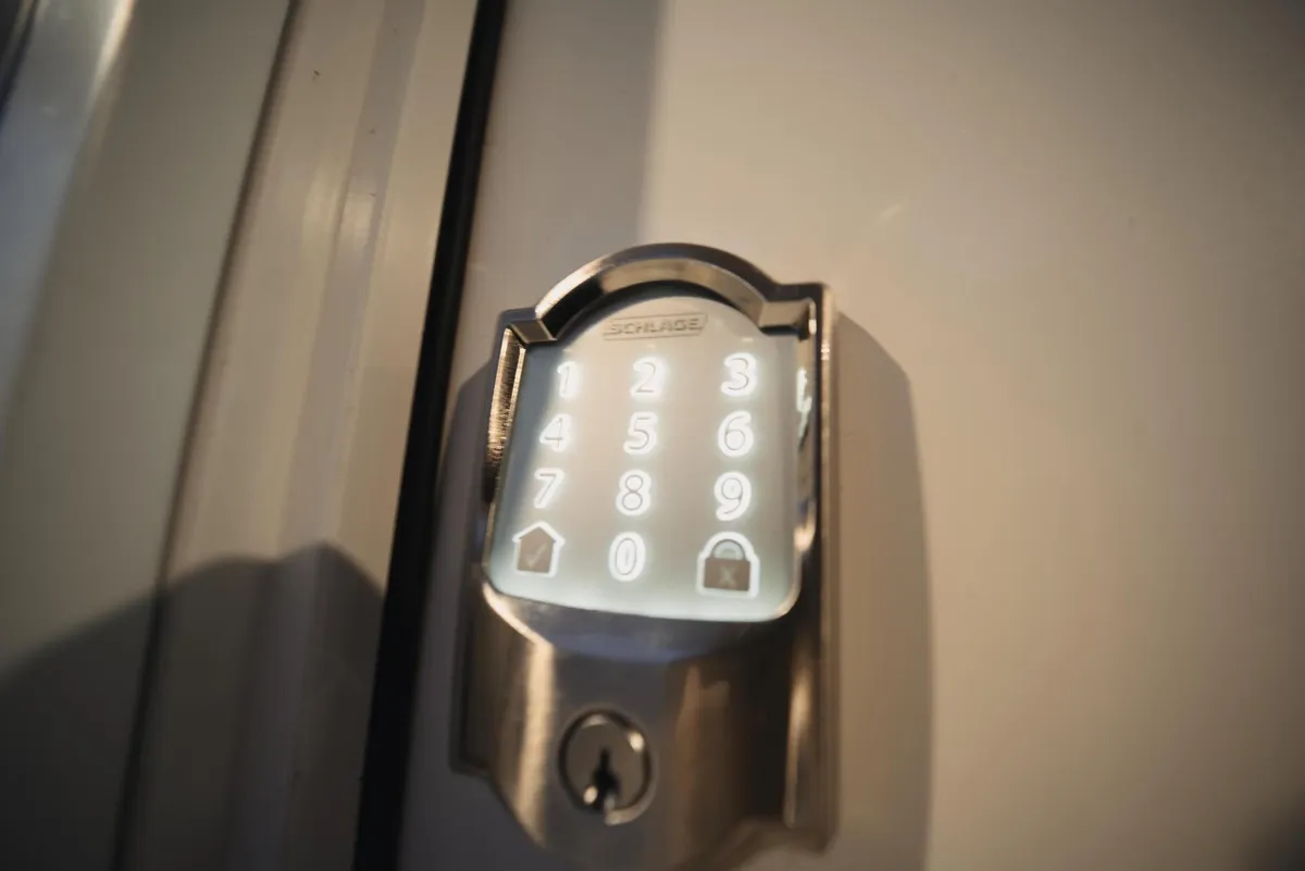 A close-up of a modern keypad lock on the studio's entrance door, signaling secure and convenient access. The clean lines and tech-forward design complement the rustic charm of the property, offering peace of mind for guests.